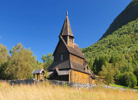 Beautiful Wooden Stave Church Of Urnes Surrounded By Mountains And Trees At Lustrafjord On A Sunny Summer Day With A Clear Blue Skyの写真素材