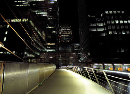 View From The South Quay Footbridge To The Brightly Lit Bank Towers Of Canary Wharf London England At Nightの写真素材