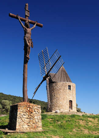 Christ Statue In Front Of The Ancient Windmill Moulin Saint Roch In The Hills Of Grimaud In Provence France On A Beautiful Autumn Day With A Clear Blue Skyの写真素材