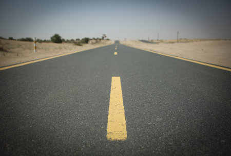 asphalt road in the middle of the desert with a yellow lineの写真素材
