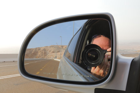 Photographer in the rear view mirror of a car on the roadの写真素材