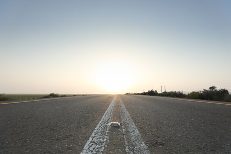 Asphalt road and the sky with clouds at sunset, closeup of photoの写真素材