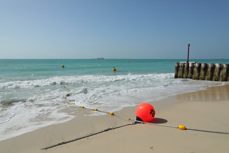 A red buoy on a sandy beach with the sea in the backgroundの写真素材