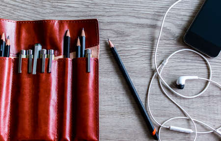 Nice brown pen leather housing with a phone and earphones on a gray backgroundの写真素材