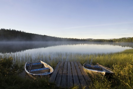 Moored boats in Lake Tevsjon near the Swedish village Ljusnedal early in the morningの写真素材