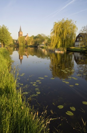 View over th river Graafstroom to the church of the small village Bleskensgraaf in the Dutch region Alblasserwaardの写真素材