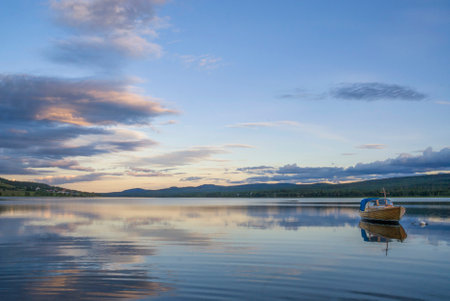 A small boat lying in lake Funasdalssjon just before the start of a beautiful sunsetの写真素材