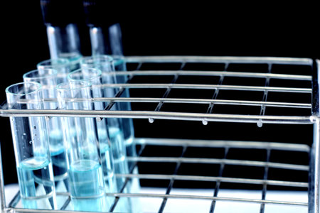 Test tubes with blue solution in rack on black background. Laboratory and testing concept.