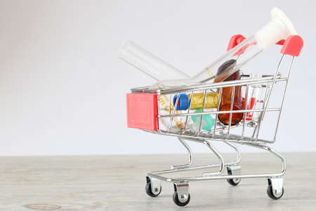 Shopping cart with test tubes on table against light background. Space for textの写真素材