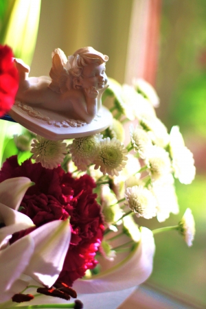 Angel cupid floating amongst flowers, set against sunny backdropの写真素材