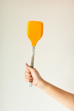 A hand holding a yellow spade of frying pan on white background.の写真素材