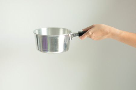 A Hand hold a handle of stainless pot prepare for cooking, on white background.の写真素材