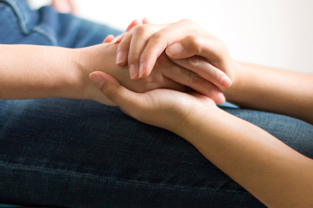 Close-up of one person holding hands for give more hope and spirit to another.の写真素材