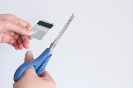 A person is cutting a credit card with scissors on white background with copy space; concept of...