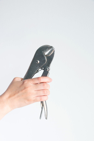 Vertical image of a hand is holding pincers pliers on white background with copy space.の写真素材