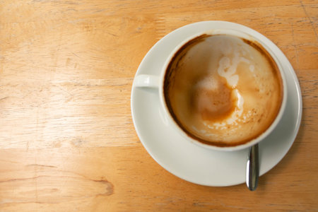 Top view of coffee cup that finished drinking on wooden table; leave brown coffee stain at bottom...