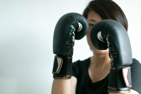 A woman in boxing gloves on fist; in posture of boxing safeguard with an eye catching at the target;...