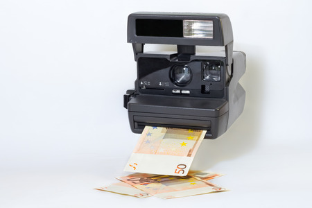 Old camera printing out cash, money earning conceptの写真素材