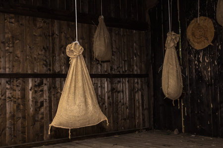 bags of jute fabric are hanging on a rope in a wooden barn