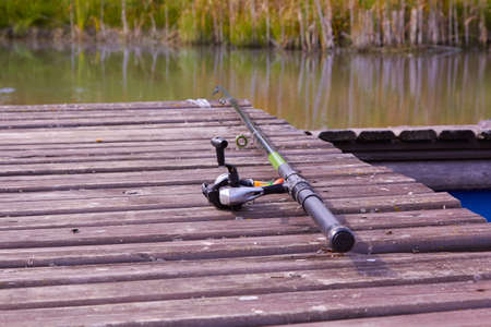 fishing rod lying on a wooden bridge by the pondの写真素材