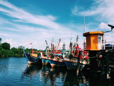 A colorful scene taken at the fishing village where all the fishing boats docked at the jetty.の素材