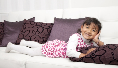 Happy thoughtful girl lying on sofa の写真素材