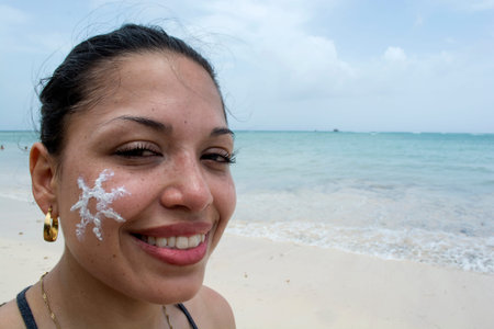 Beauty Girl Applying Sun Tan Cream on her Face.