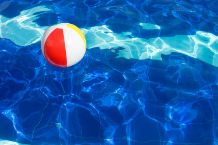 Beach ball floating in swimming pool abstract concept for summer vacations.
