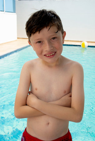 Portrait of a little boy in swimming shorts holding a beach ball.の写真素材
