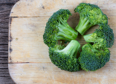Bunch of fresh green broccoli on wood chopping blockの写真素材