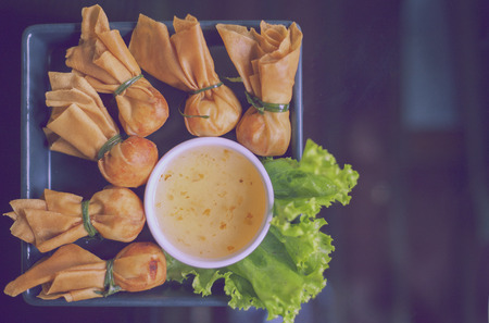 Toong thong,Thai food, oriental deep fried wontons filled with prawn and spring onion, served with dumpling and sauces,vintage colorの写真素材