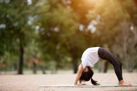 beautiful little asian child girl doing yoga in the public park.