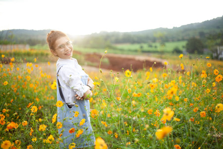 Beautiful young hipster writing in a notebook outdoors in flower garden in sunset background