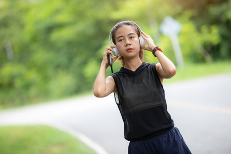 A young woman warms up on a treadmill during her morning workout, her steps rhythmic and steady, as the dawn light streams through the gym windows, illuminating her commitment to a healthy start to the day.の写真素材