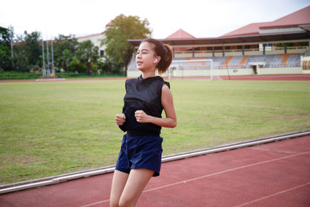 A young woman warms up on a treadmill during her morning workout, her steps rhythmic and steady, as...