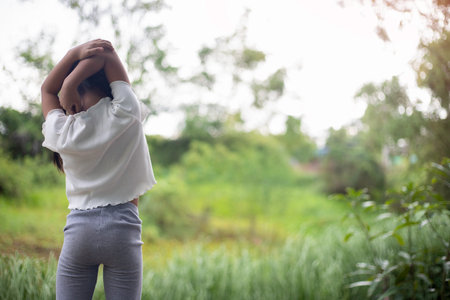 A little girl practices yoga in the backyard, surrounded by the refreshing embrace of nature, her movements harmonizing with the gentle sounds of birds and rustling leaves as sunlight streams through the trees.の写真素材