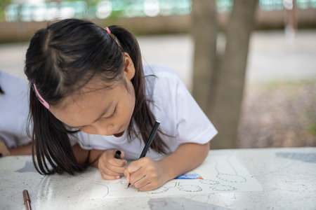 young girls are sitting at a table with markers and coloring books. They are drawing and coloring...