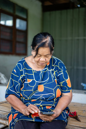 A woman in a blue shirt is sitting at a table with a tablet in front of her.の写真素材