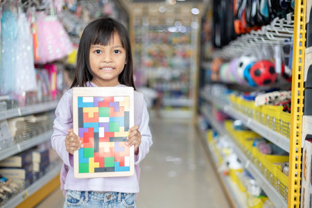 A young girl is holding a puzzle in a store. The puzzle is a jigsaw puzzle with a picture of a...