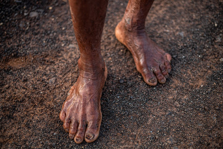 A man's feet are covered in mud and dirt. Concept of hardship and struggle, as the man's feet are dirty and worn, possibly from walking long distances or working in difficult conditionsの写真素材