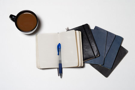 Stacked isolated worn notebook journals with pen and coffee