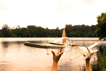 children's hands playing with a plane built with recycled material (wood, PVC bottles, cardboard)の写真素材
