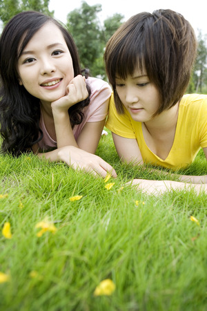 Two girls sprawling on lawnの写真素材