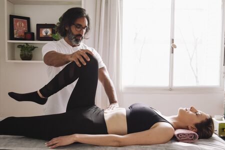 kinesiologist raising the knee of a beautiful womanの写真素材