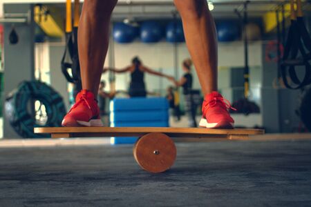 Detail of a person's legs practicing balance on a crossfit balance board in a gymの写真素材