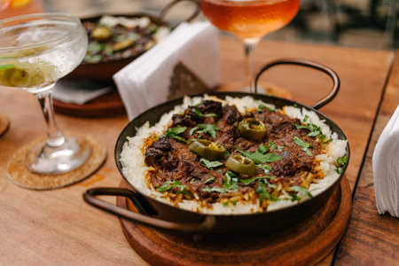 Detail of a pan with rice and beans decorated with chopped green chilies and served in a wooden...