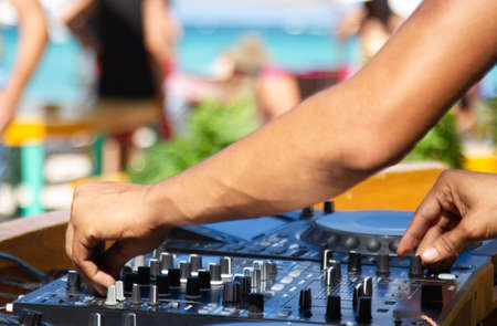 Hand of a sound technician adjusting the sound table parameters outdoors in a beach party with the sea on the backgroundの写真素材