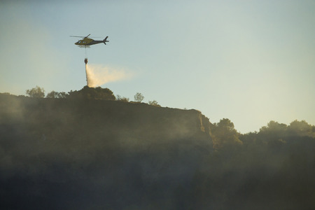 GRANADA, AUGUST 28: Fire fighting Helicopter, with bambi basket, during a fire fighting in the bush. August 28, 2014, Granada, Spain.のeditorial素材