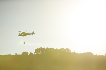 GRANADA, AUGUST 28: Fire fighting Helicopter, with bambi basket, during a fire fighting in the bush. August 28, 2014, Granada, Spain.のeditorial素材