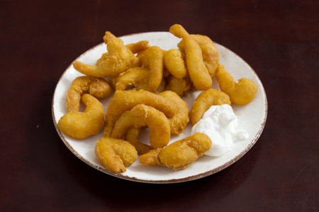 A plate of fried shrimp with a dollop of whipped cream on top. The shrimp are golden brown and...